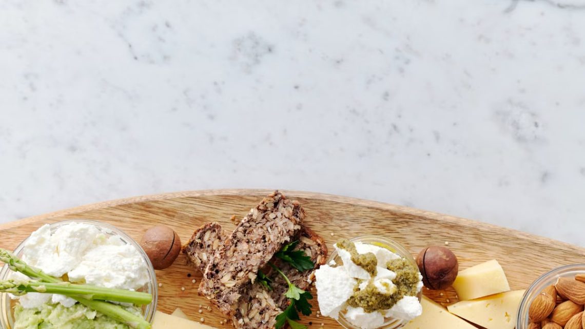 Top view of a gourmet cheese and cracker platter with nuts, ideal for healthy snacking and elegant serving.